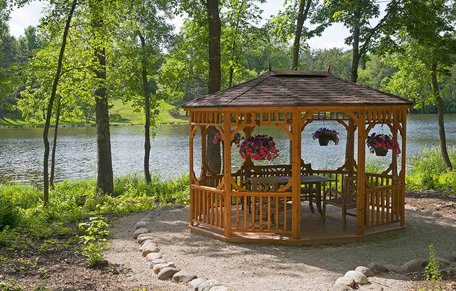 wooden gazebo surrounded by trees overlooking a lake