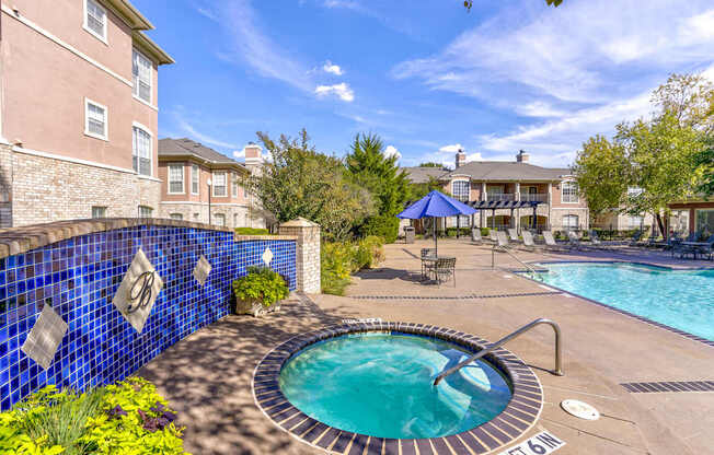 A blue tiled wall surrounds a hot tub in a backyard.