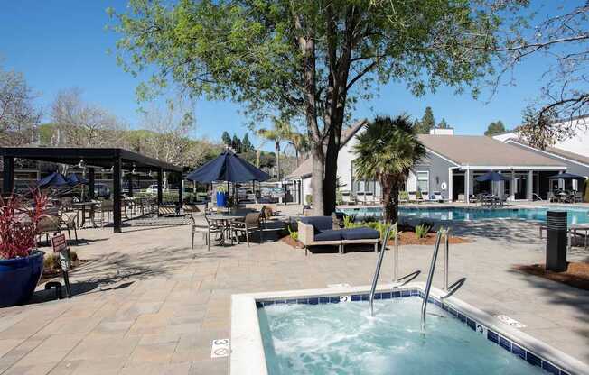 A pool area with a hot tub and a tree at Kirker Creek Apartments, Pittsburg, California