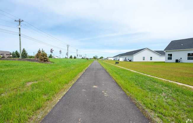 A long, straight road stretches into the distance with houses on either side.