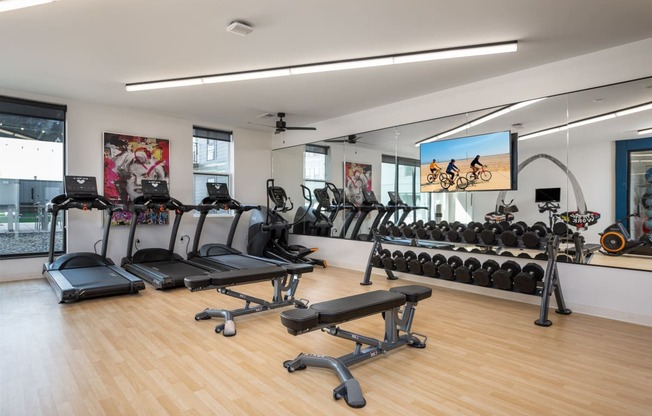 a gym with cardio equipment and mirrors on the wall