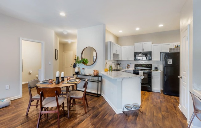 a kitchen and dining area with white cabinetry and black appliances