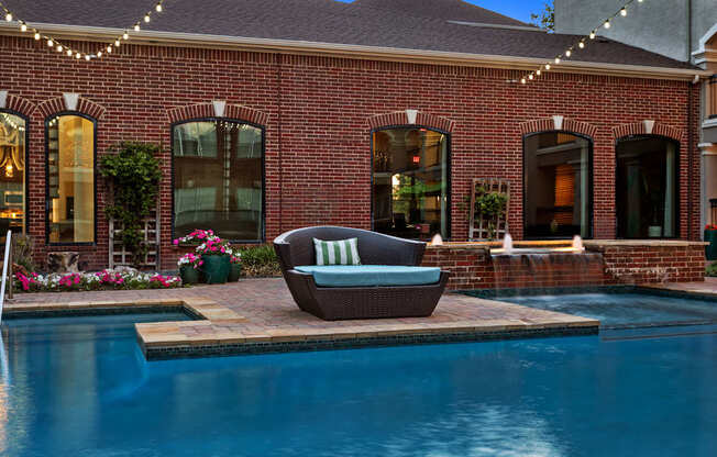 A pool with a chair and lights around a house.