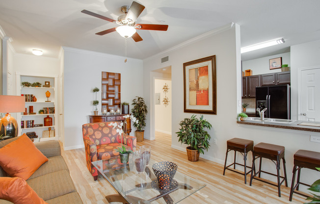 View of Living Room with Plank Wood Flooring, Ceiling Fan, and View of Kitchen at Raveneaux Apartments