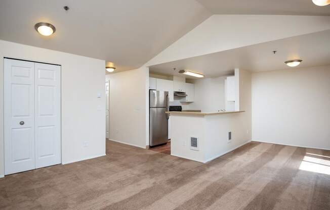 the living room and kitchen of an empty apartment with a stainless steel refrigerator