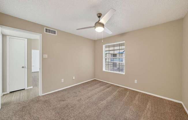 A room with a carpeted floor and a ceiling fan.