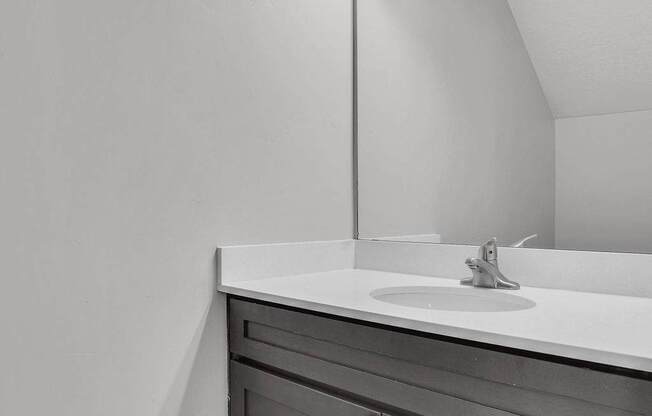 A bathroom with a white sink and a mirror with lights above it.