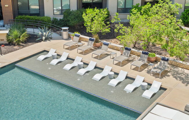A large swimming pool surrounded by sun loungers and chairs.