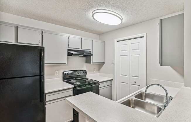 Apartment kitchen with black appliances and white cabinets at Wellington Farms, Charlotte, North Carolina