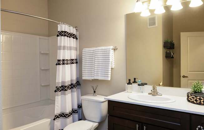 A bathroom with a white toilet, a sink, and a shower curtain.