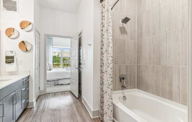 a bathroom with a tub and a shower and a door to a bedroom