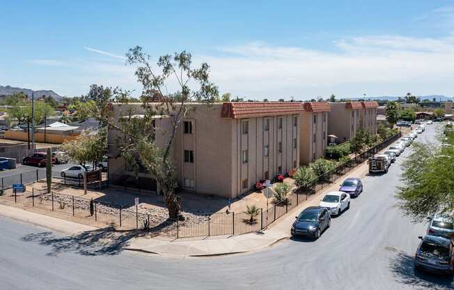 A street view of a residential area with apartment buildings and parked cars.