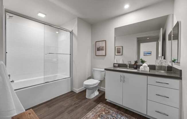 a bathroom with a shower toilet and sink and a mirrorat Westbury Apartments, California