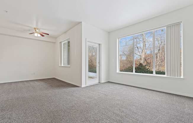 A room with a carpeted floor and a ceiling fan.