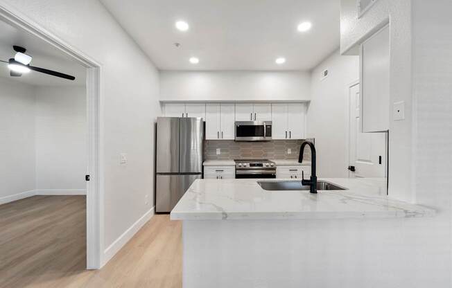 A modern kitchen with a white countertop and stainless steel appliances.