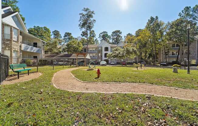 A sunny day at a park with a playground and apartment buildings in the background.