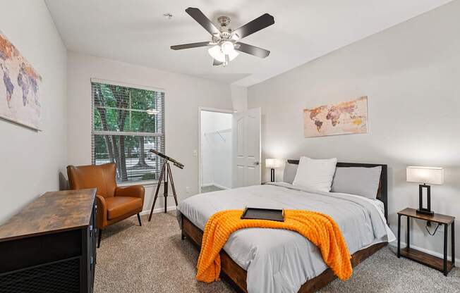 A bedroom with a bed, chair, and a ceiling fan.