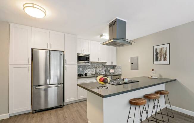 Kitchen with stainless steel French door fridge, microwave and breakfast bar with an electric top stove and range hood