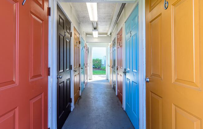 A hallway with doors on both sides leading to a grassy area.