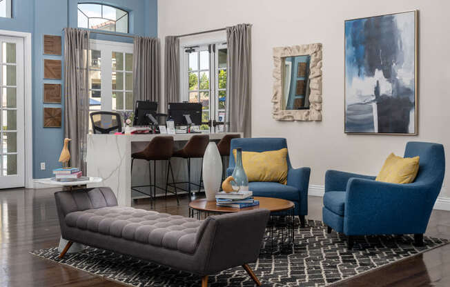 A living room with a grey sofa, a blue armchair, a coffee table, and a painting on the wall.
