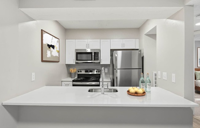 A modern kitchen with a stainless steel refrigerator and a white countertop.