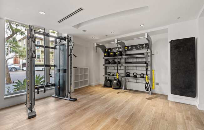 a gym with weights and a large window and a wooden floor