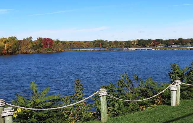A lake surrounded by trees with a rope fence in the foreground.