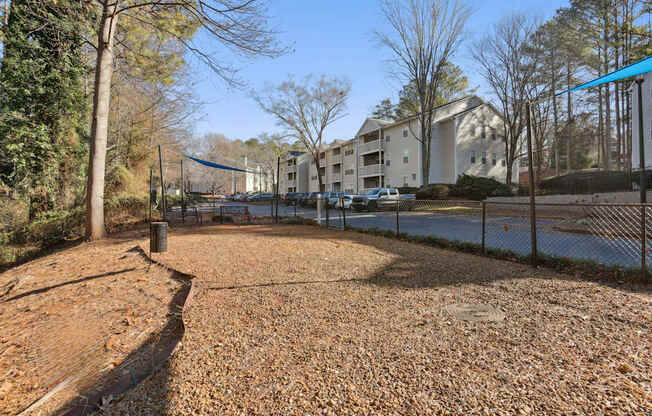 A playground with a blue tarp in the background and a building in the distance.
