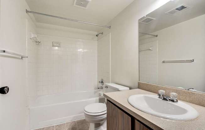 A white bathroom with a toilet, sink, and bathtub.