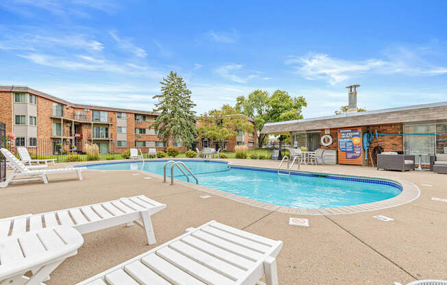 A pool area with sun loungers and a building in the background.