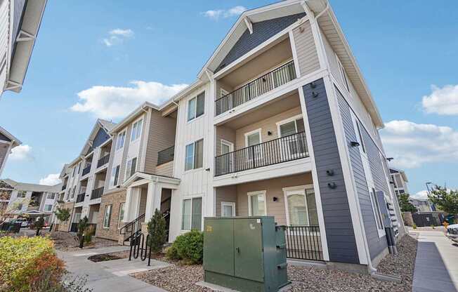 A modern apartment building with a green utility box in front. at Connect at First Creek Apartments, Denver, CO, 80249