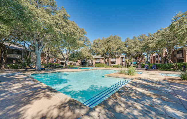 A swimming pool surrounded by trees and houses.