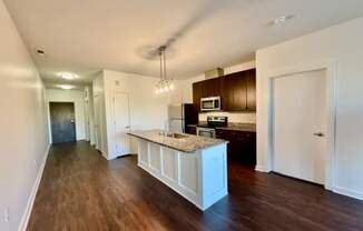 A kitchen with dark wood floors and white cabinetry.