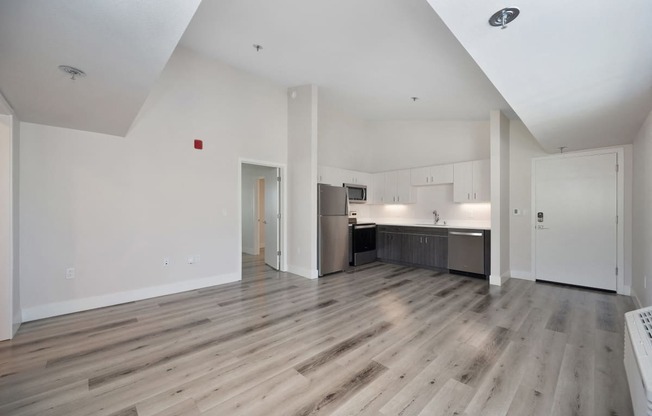 the living room and kitchen of an apartment with wood floors and white walls  at Track 281 Apartments, Sacramento, CA