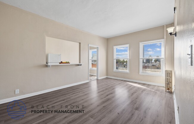 A spacious room with wooden flooring and a view of K-town through the windows.