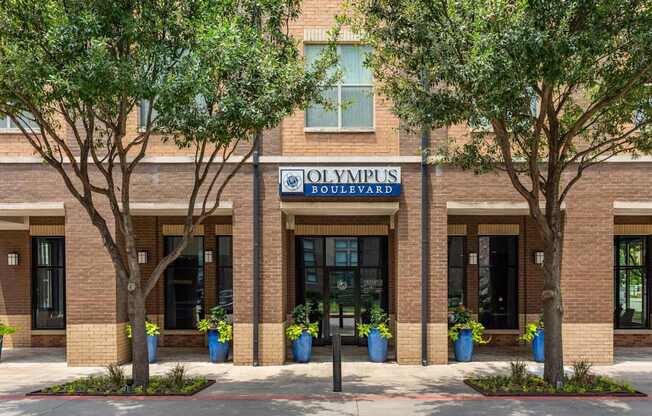 Olympus Boulevard building with trees and potted plants in front.