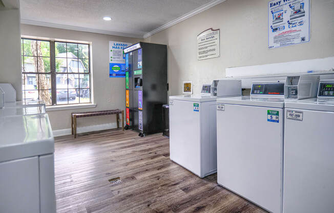 a laundry room with four washes and dryers in it and a window