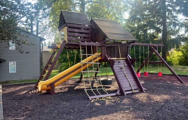 A wooden playground structure with a yellow slide.
