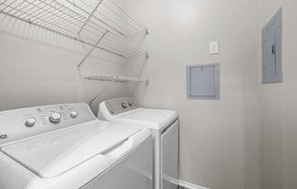 a washer and dryer in a laundry room with a shelf on the wall