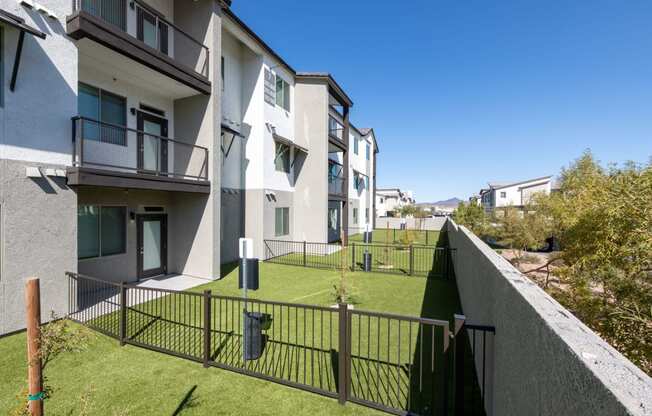 a view of an apartment complex with a green lawn and a fence