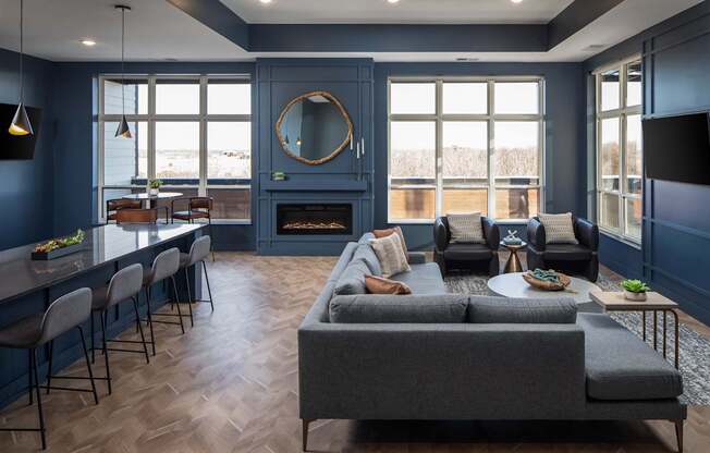 A living room with a grey couch and a fireplace.