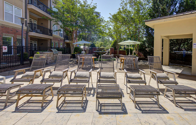 A patio with chairs and tables is surrounded by trees and buildings.
