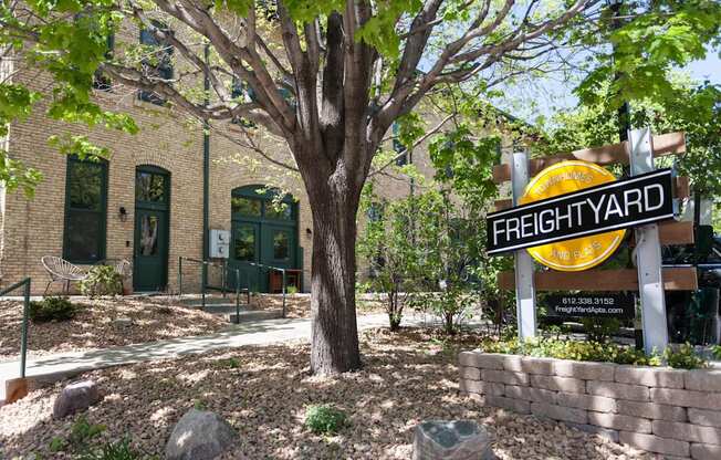 Angled image of FreightYard building exterior of exposed brick with large tree in front.