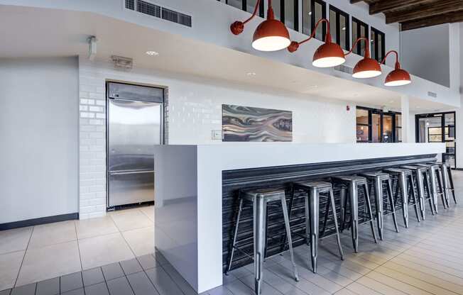 a row of bar stools in front of a long bar with white tiles at Ashford Belmar Apartments, Lakewood, 80226