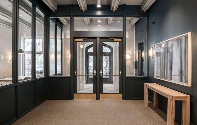 a lobby with black walls and doors and a wooden bench