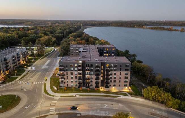A large building is situated on a road with a body of water in the background.