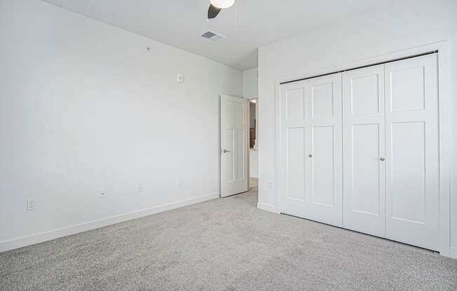 A bedroom with a carpeted floor and large closet at Meadowbrooke Apartment Homes in Kentwood, MI 49512