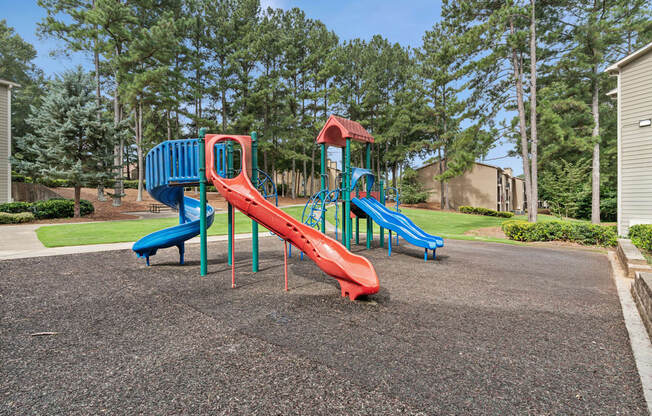 A playground with a red slide and blue slide.