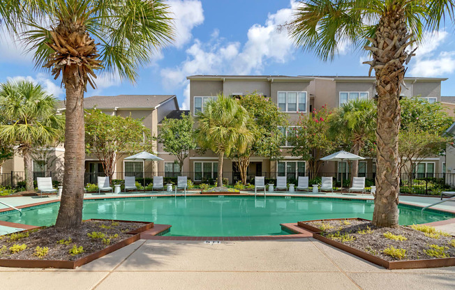 a swimming pool with palm trees and a building in the background at Summerwind, Pearland, TX 77584