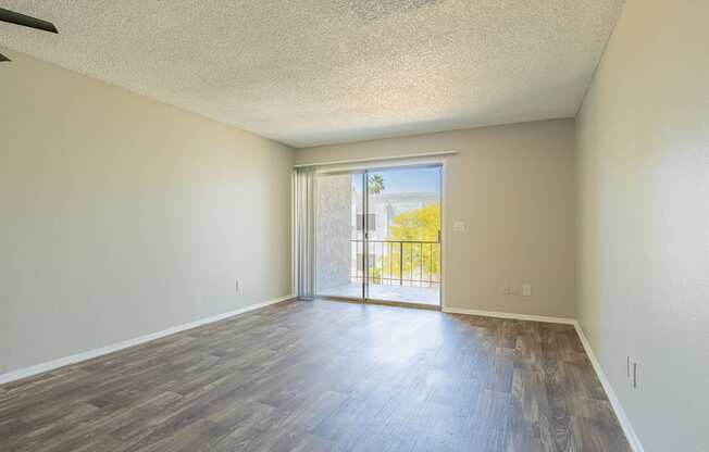 a bedroom with hardwood flooring and a sliding glass door leading to a balcony